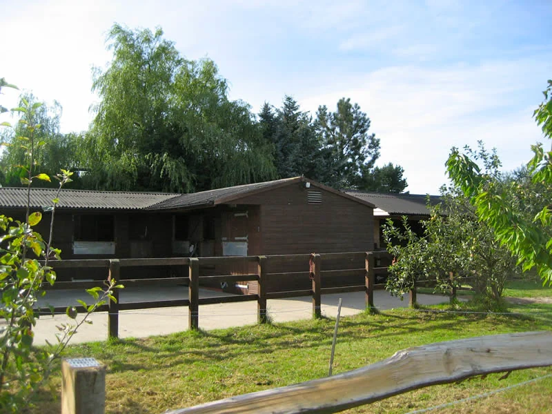 Wooden stables and leafy trees at Ardenvale